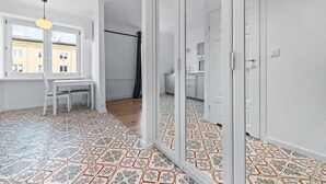 Une pièce dotée d’une grande fenêtre, d’une table à manger avec des chaises, d’un miroir et d’un sol à motifs.