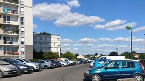 Un parking avec plusieurs voitures, une voiture bleue étant visible au premier plan.