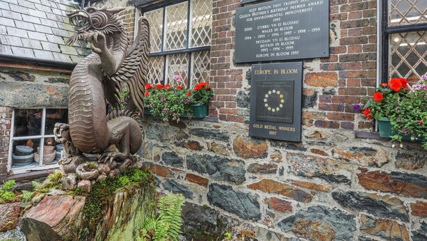 A stone building with a plaque listing environmental awards and a decorative dragon sculpture.