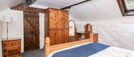 A bedroom with a wooden bed, a dresser, a mirror, and a wardrobe.