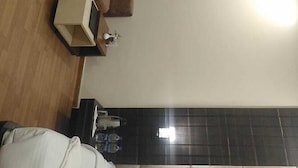 A modern hotel room with a brown sofa, a small table, and a bed. - Hotel New Grand (Deoghar)