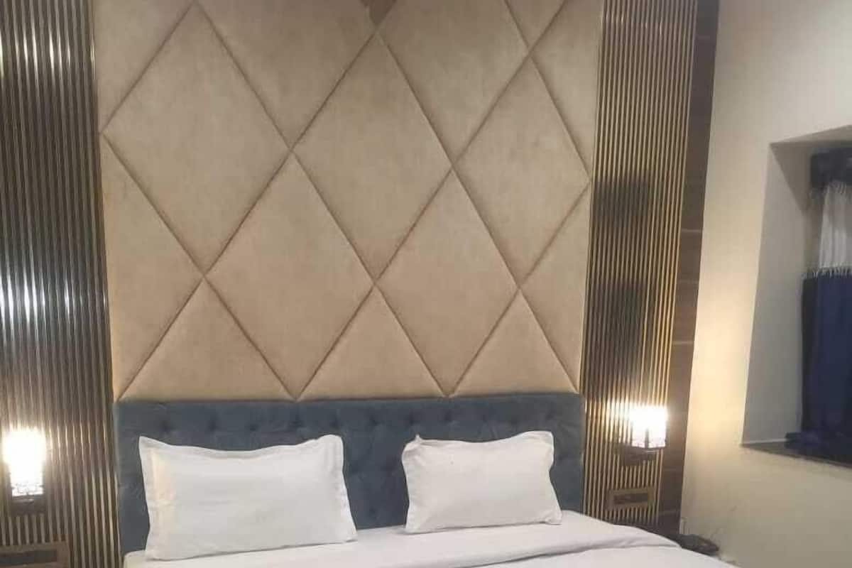 Una habitación de hotel con una cama, una manta roja y un cabecero con diseño de rombos.
