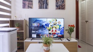 A living room with a flat-screen TV, potted plants, and a bookshelf.