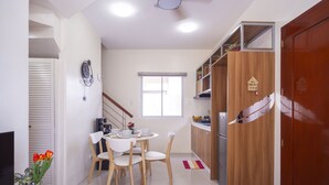 A modern kitchen with a dining area, wooden cabinets, a refrigerator, and a clock on the wall.