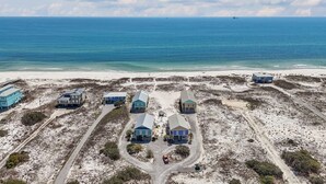 Une vue aérienne d’une zone côtière avec plusieurs bâtiments, une plage de sable et l’océan.