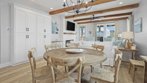 A spacious kitchen with white cabinets, a wooden dining table, and a chandelier.
