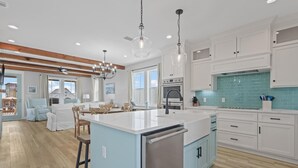 A modern kitchen with a central island, white cabinetry, and a blue backsplash.