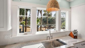 A kitchen with a large window, a sink, and a hanging light fixture. - 116 Sea Otter - Resort Access & Golf Cart! (Fripp Island)