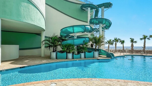 Ein Pool mit einer mehrstufigen Wasserrutsche daneben.