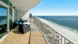 Ein Balkon mit Blick auf den Strand, Gartenmöbel und einer Geländer.