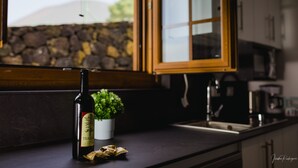 Una botella de vino, una pequeña planta en maceta y algunos objetos envueltos sobre una encimera de cocina.