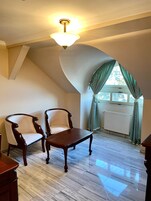 Una habitación con dos sillones tapizados, una mesa de madera y una lámpara en el techo.