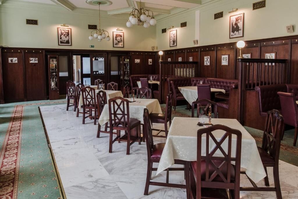 A dining area with wooden booths and tables, marble flooring, and wall-mounted picture frames.