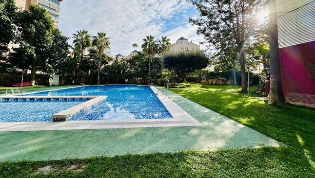 A swimming pool with a tiled deck, surrounded by greenery and buildings. - T1029 - Comfort and Style in Cala de Villajoyosa (Villajoyosa)