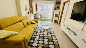 A living room with a yellow sofa, a TV, and a patterned rug. - T1029 - Comfort and Style in Cala de Villajoyosa (Villajoyosa)