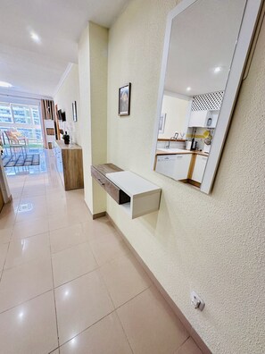 A modern bathroom with a large mirror, a white countertop, and a wooden cabinet.