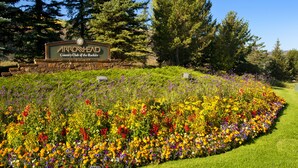 Letrero del Arrowhead Country Club of the Rockies rodeado por un colorido jardín floral.