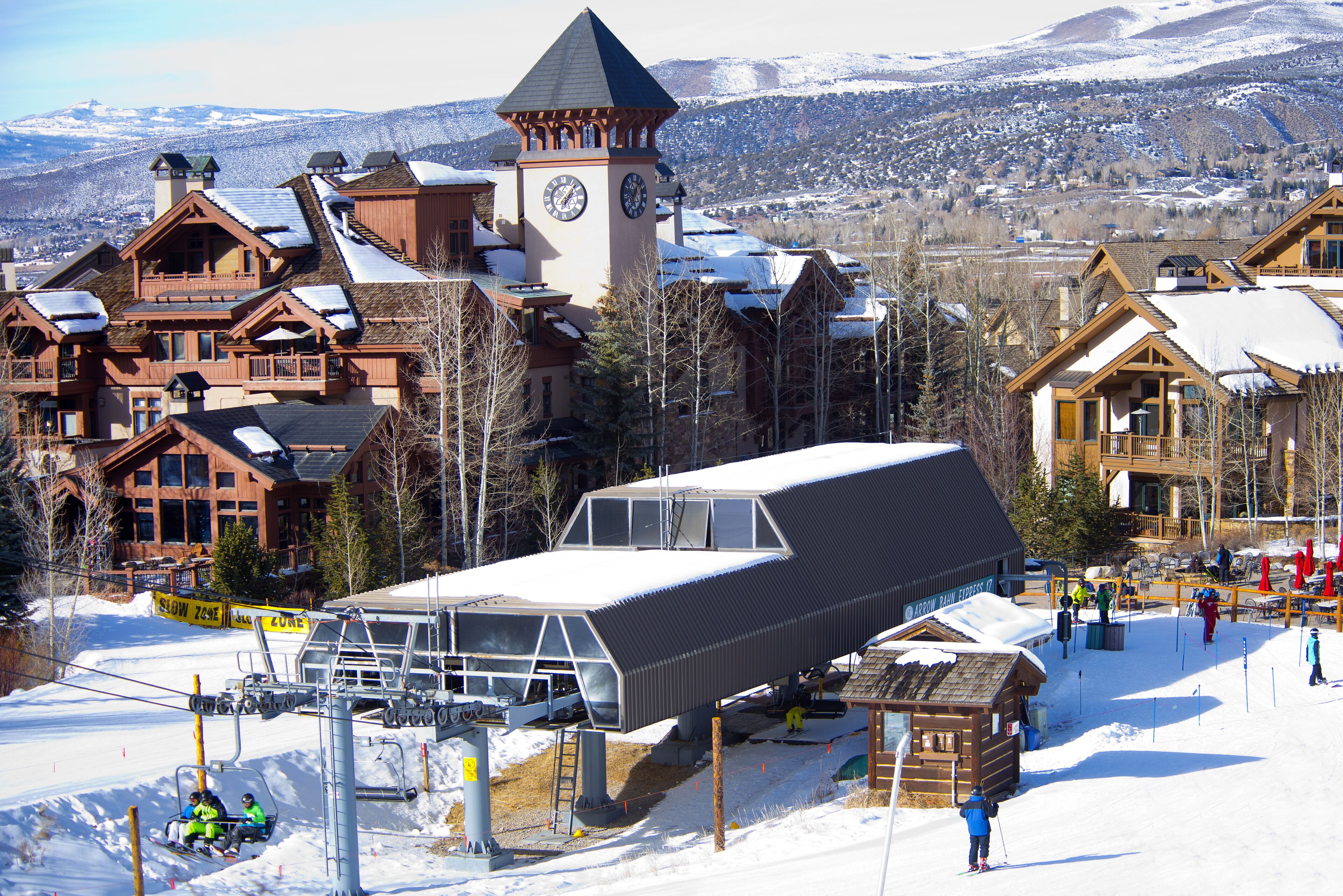 A ski resort with a ski lift, wooden buildings, and a clock tower.