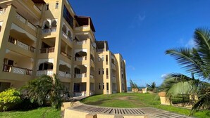 Un hôtel à plusieurs étages doté de balcons, d’une cour verdoyante et de palmiers.
