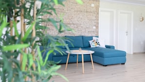 Ein modernes Wohnzimmer mit einem blauen Ecksofa, einem runden Couchtisch und einer Ziegelwand.