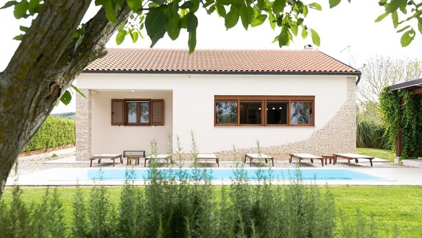 Ein modernes Haus mit Swimmingpool, einer Terrasse und Lounge-Möbeln sowie einer Ziegel-Fassade.
