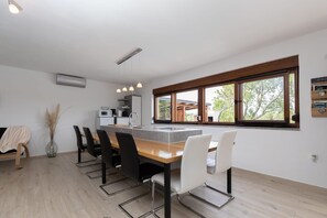A modern kitchen with a central island, dining chairs, and a large window. - Villa Casa Kalandra Zadarvillas (Rovinj)