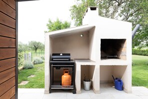 An outdoor grill with a chimney, a gas tank, and a bucket. - Villa Casa Kalandra Zadarvillas (Rovinj)