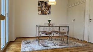 A dining area with a table and chairs, a painting on the wall, and a door in the background.