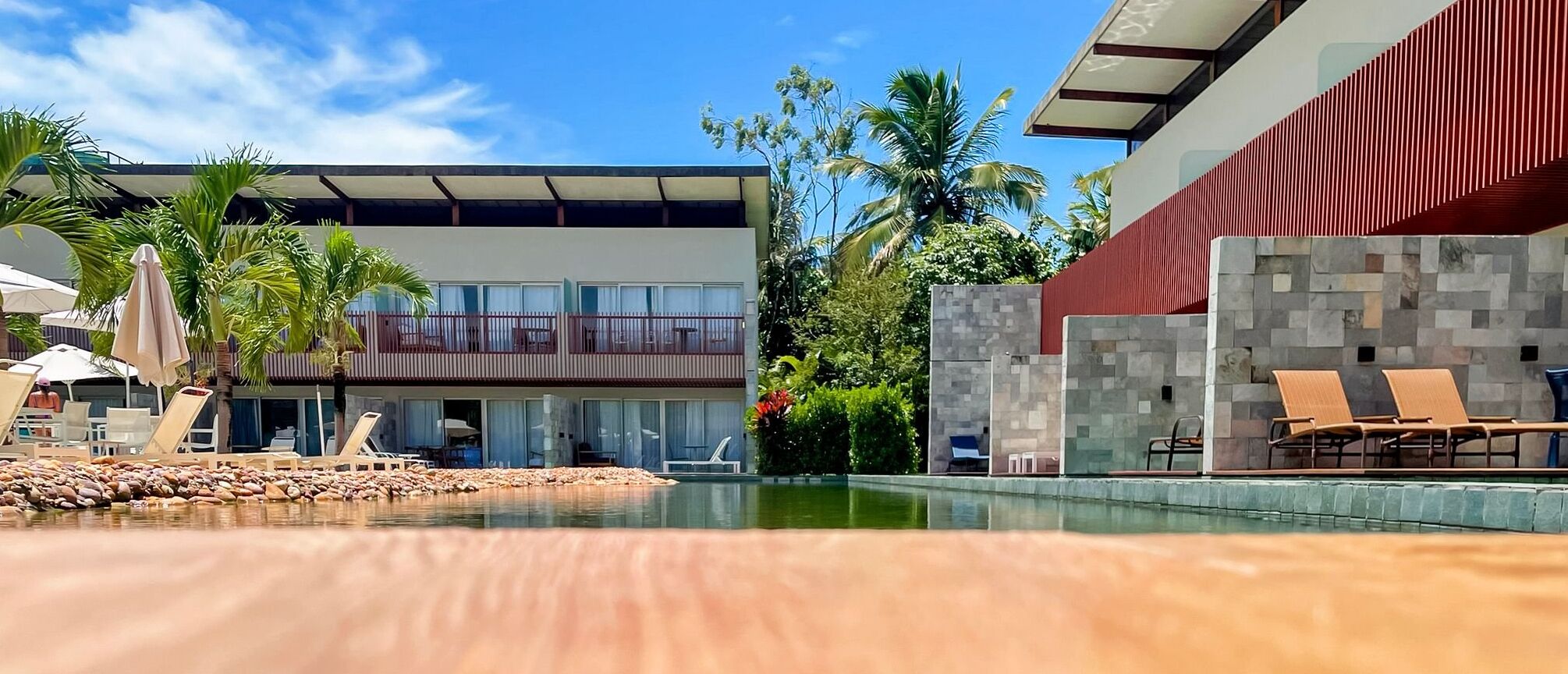 Un hôtel moderne doté d’une piscine, de chaises longues et de palmiers.