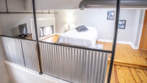 A bedroom with a bed, a nightstand, a lamp, and a window with curtains. - Lafayette Vibe Downtown District (Lafayette)
