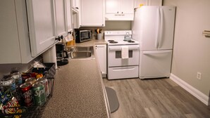 A compact kitchen with white cabinets, a microwave, a stove, and a refrigerator. - Lafayette Vibe Downtown District (Lafayette)