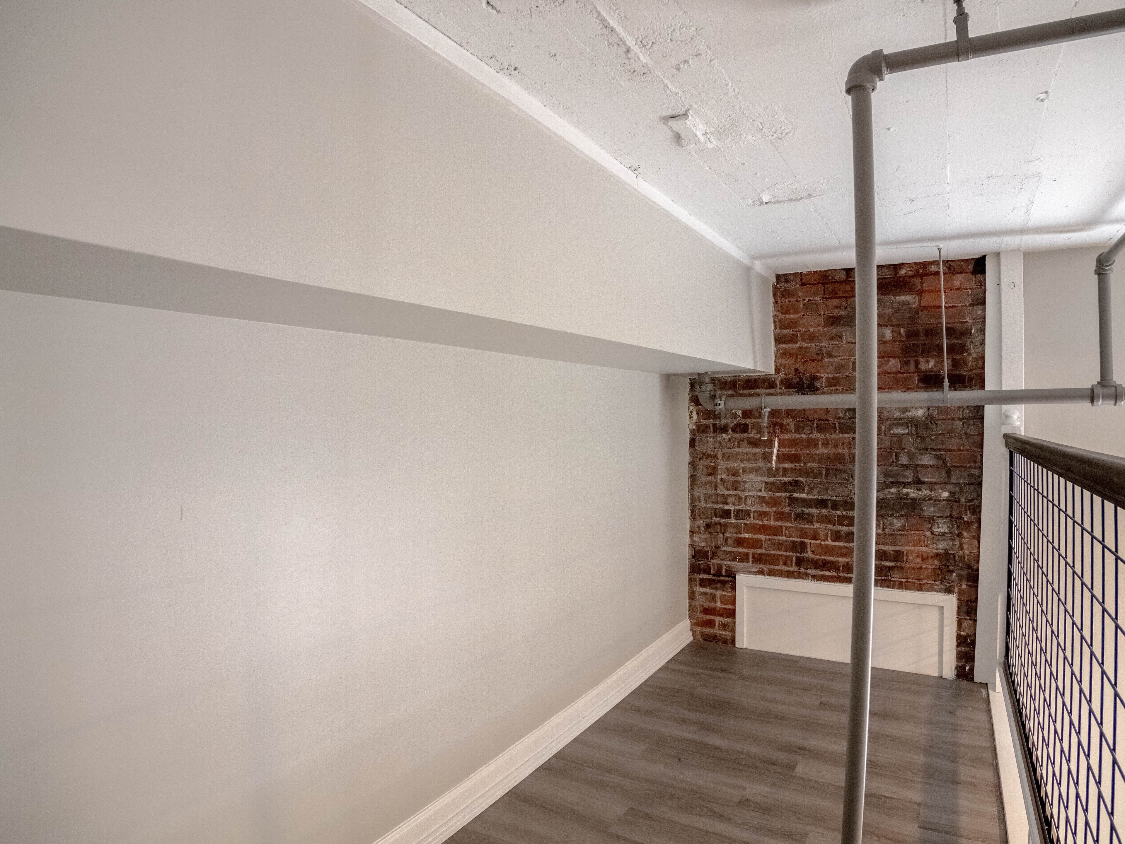 A staircase with a wooden floor and a brick wall.
