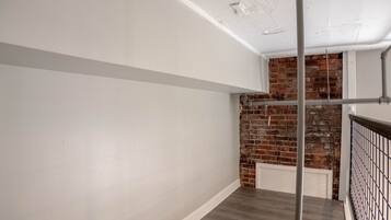 A staircase with a wooden floor and a brick wall.