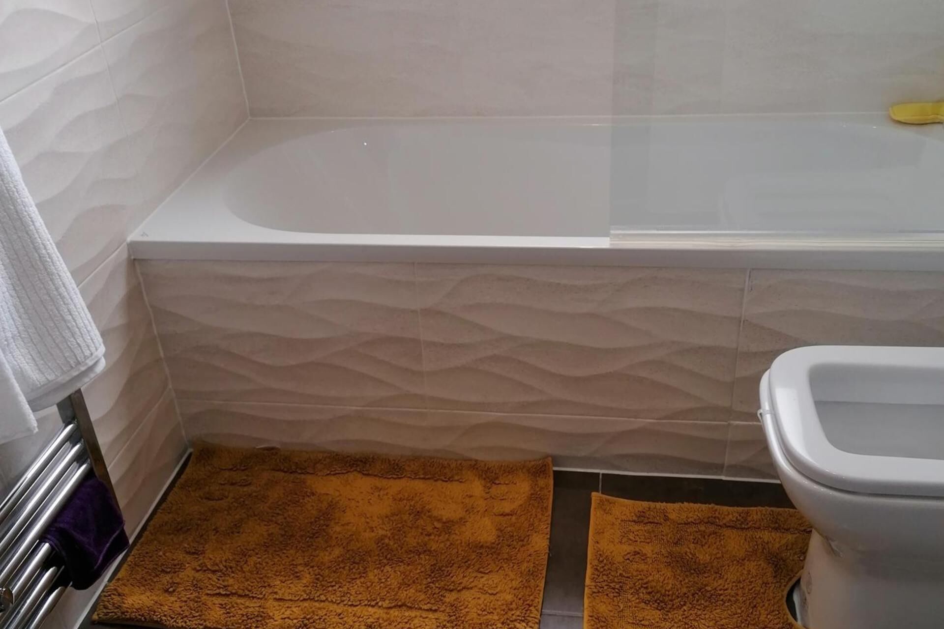 A bathroom with a bathtub, a toilet, and a towel rack.
