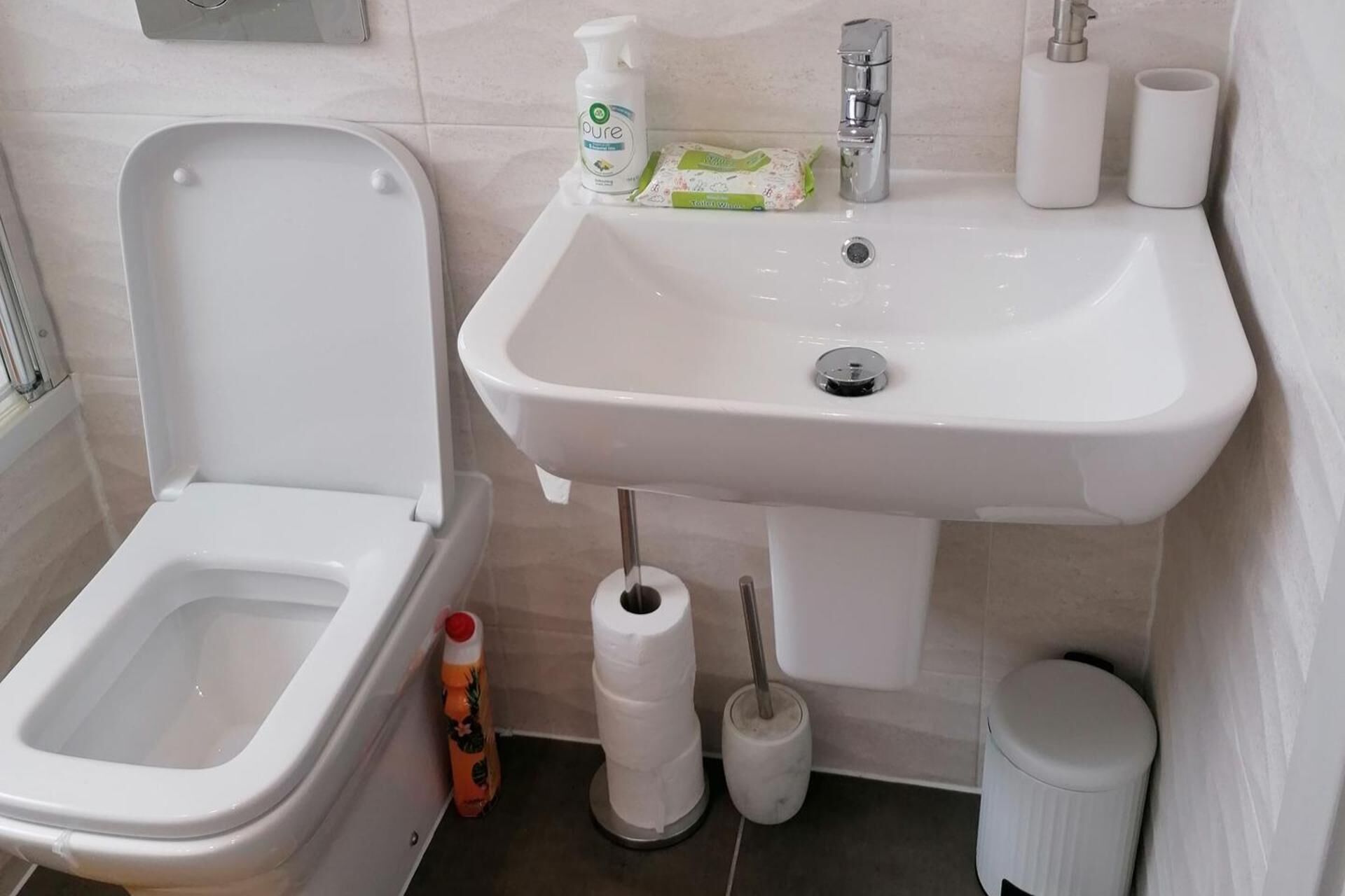 Une salle de bain équipée de toilettes, d’un lavabo et de papier toilette.