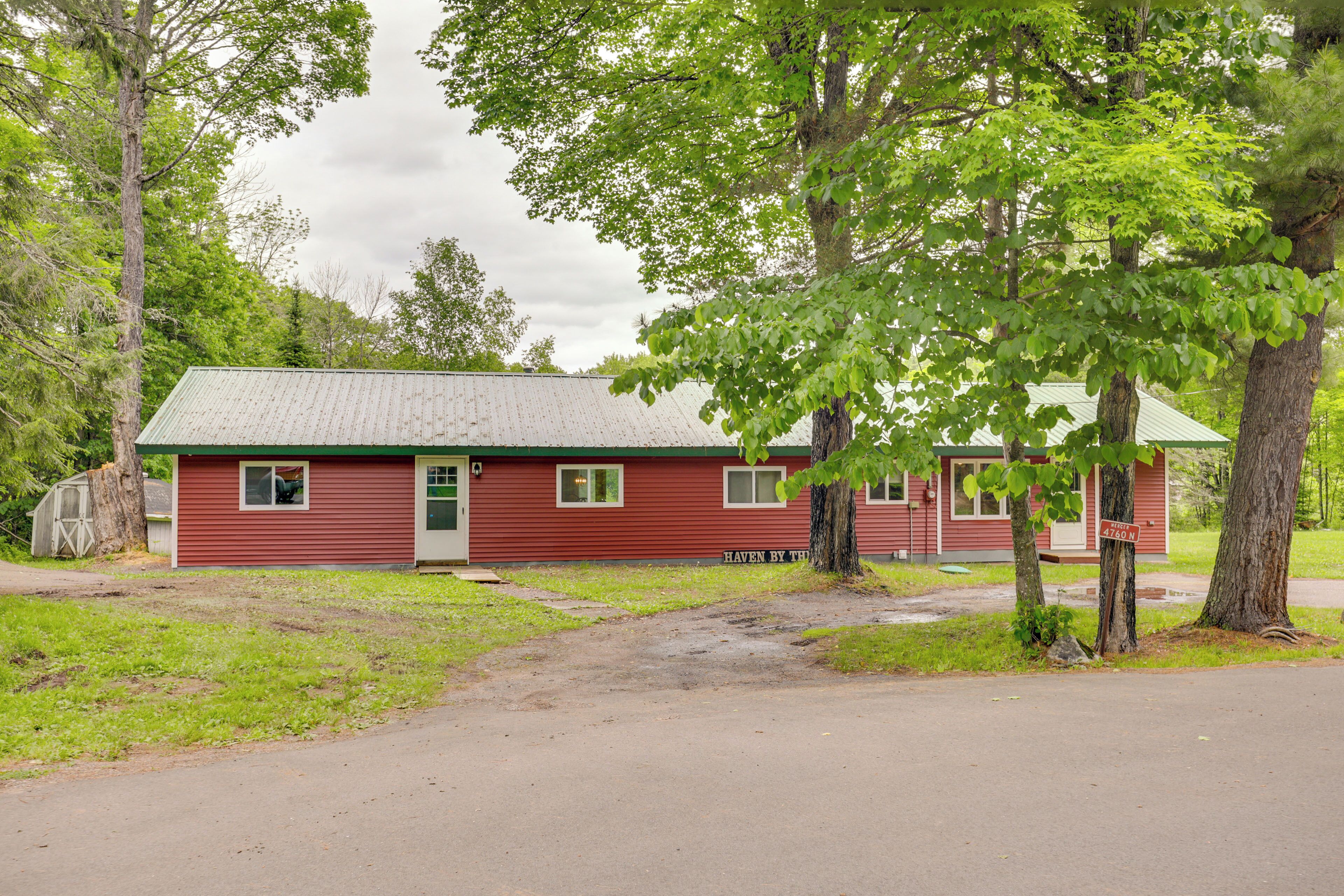 A red building with a green door, surrounded by trees and a grassy area.