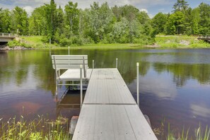 A wooden dock extending into a calm lake, surrounded by lush greenery and trees.