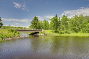 A river with a bridge, surrounded by greenery and trees.