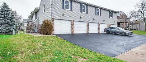A two-story residential building with a garage, a driveway, and a parked car.
