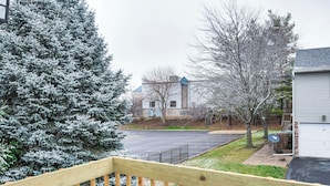 A residential area with a snow-covered evergreen tree, a paved driveway, and a house with a garage. - Welcoming Condo in Davenport: Central Location! (Davenport)