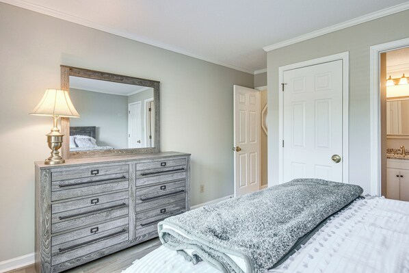 Un dormitorio con cama, cómoda, espejo y puerta.
