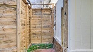 A wooden outdoor shower area with a hose and showerhead, adjacent to a white RV-style building. - 1 Mi to Surfside Beach: Coastal Cottage (Murrells Inlet)
