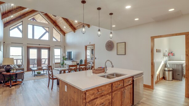 Una cocina amplia con una isla grande, muebles de madera y un techo alto con vigas a la vista.