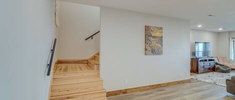A modern interior with a wooden staircase, a dining area, and a kitchen.