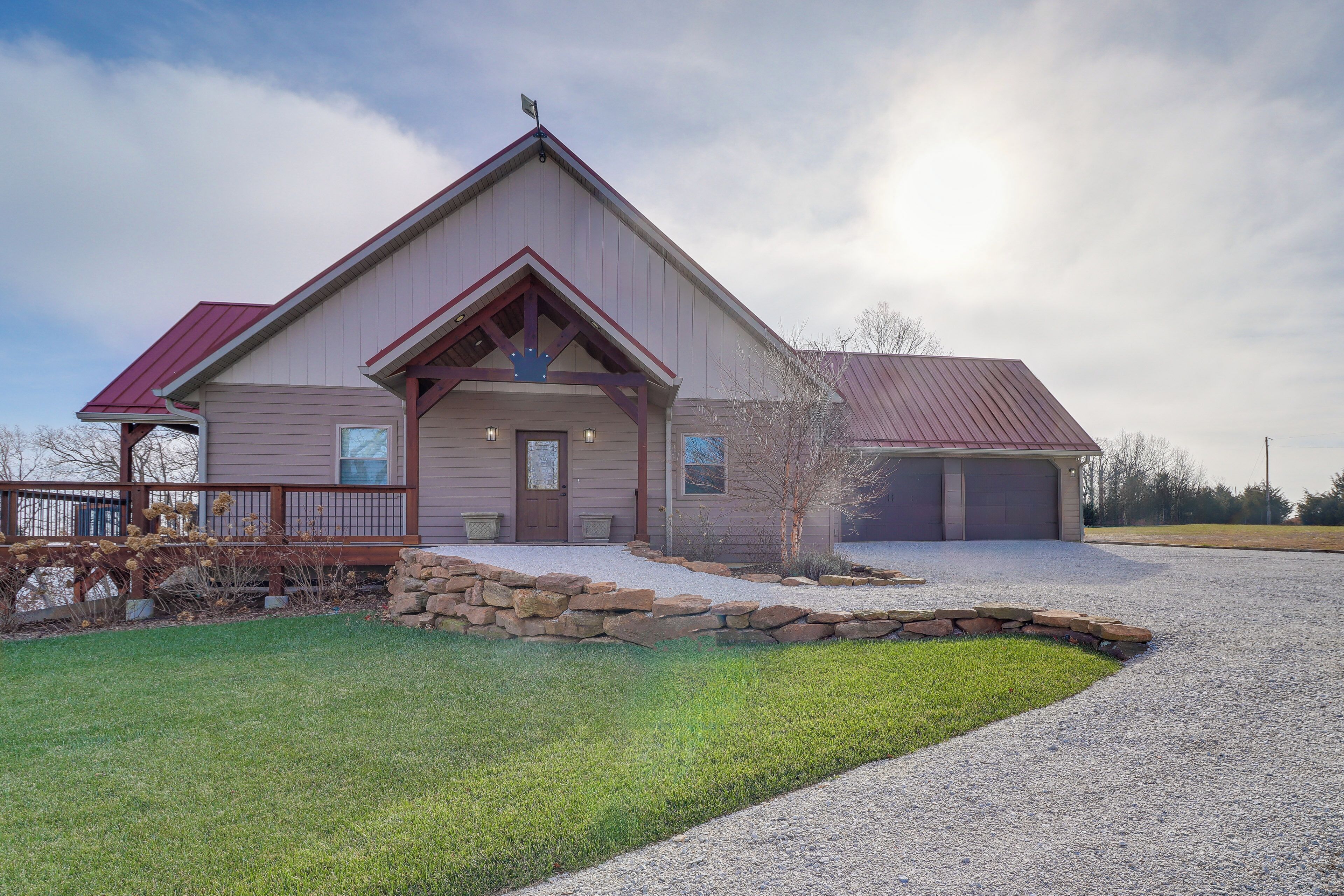 A two-story house with a stone foundation, a red roof, and a front porch.