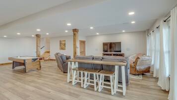 A spacious living area with a pool table, a sofa, and a TV.
