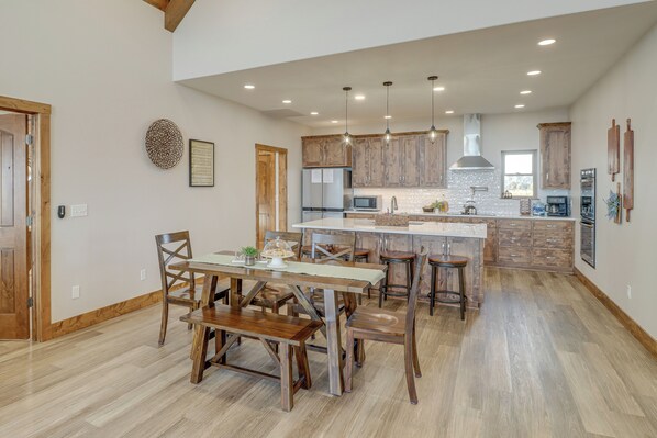 A spacious kitchen with wooden cabinets, a central island, and pendant lighting. - Spacious Harrison Vacation Rental w/ Deck & Views! (Harrison)