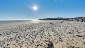 A wide sandy beach with footprints, a clear sky, and a distant shoreline. - Tranquil Ogunquit Condo: Walk to Beach & Marina! (Ogunquit)
