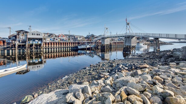 A waterfront dock with boats, a bridge, and buildings. - Tranquil Ogunquit Condo: Walk to Beach & Marina! (Ogunquit)