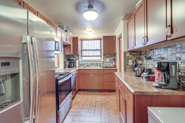A modern kitchen with stainless steel appliances, wooden cabinets, and a tiled backsplash.